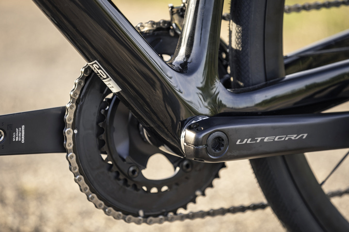 Nahaufnahme eines Fahrradgetriebes mit Shimano Ultegra Kurbelarm an einem schwarzen Rahmen. Ideal für Radsportler.