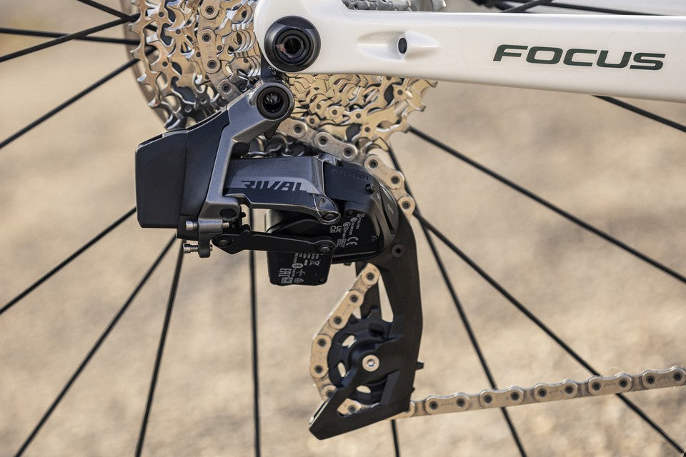 Nahaufnahme eines Focus-Rennrads mit SRAM Rival Schaltwerk und Kettensystem. Radnabe und Kettenblätter sichtbar.