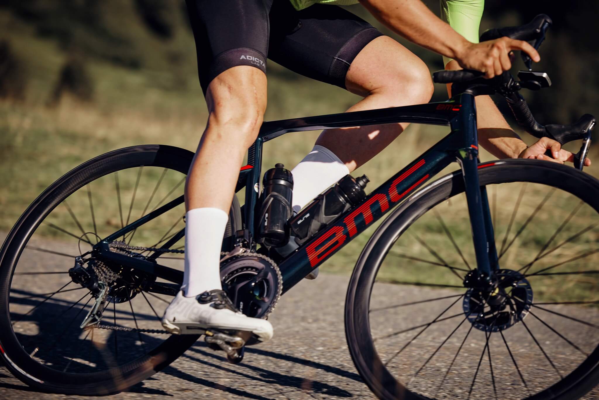 Mann fährt ein BMC Roadmachine Rennrad auf einer Straße, trägt Radtrikot und Shorts, Fokus auf Bewegung und Performance.