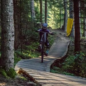 Mountainbiker auf schmalem Waldweg mit Cube Stereo One77, ausgerüstet mit Helm und Schutzkleidung, ideal für Offroad-Abenteuer.