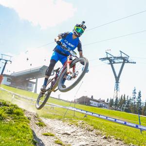 Mountainbiker springt mit einem Cube Stereo One77 über Hügel, geeignet für Downhill-Fans und Outdoor-Abenteurer.