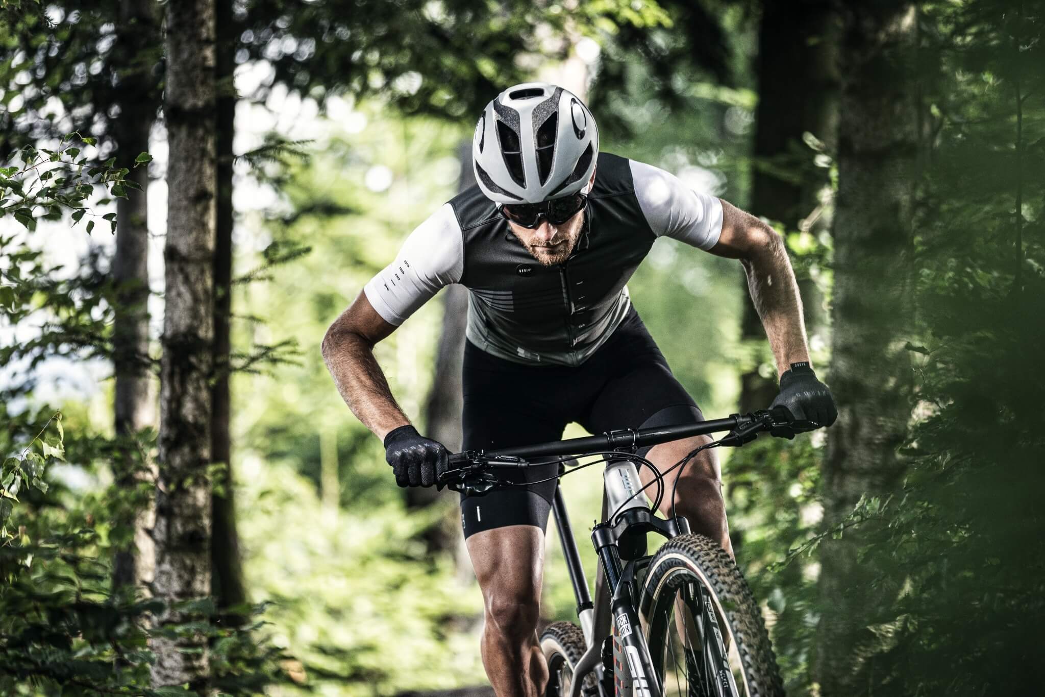 Mann im Wald auf einem BMC Twostroke Mountainbike; sportliche Ausrüstung, fokussiert auf das Fahren im Gelände.