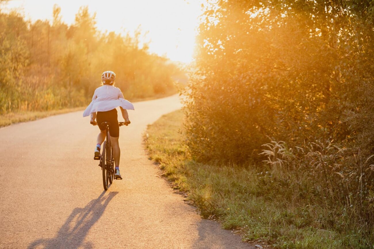 Person fährt bei Sonnenuntergang mit einem Specialized City- und Urban-Fahrrad auf einem ländlichen Weg.