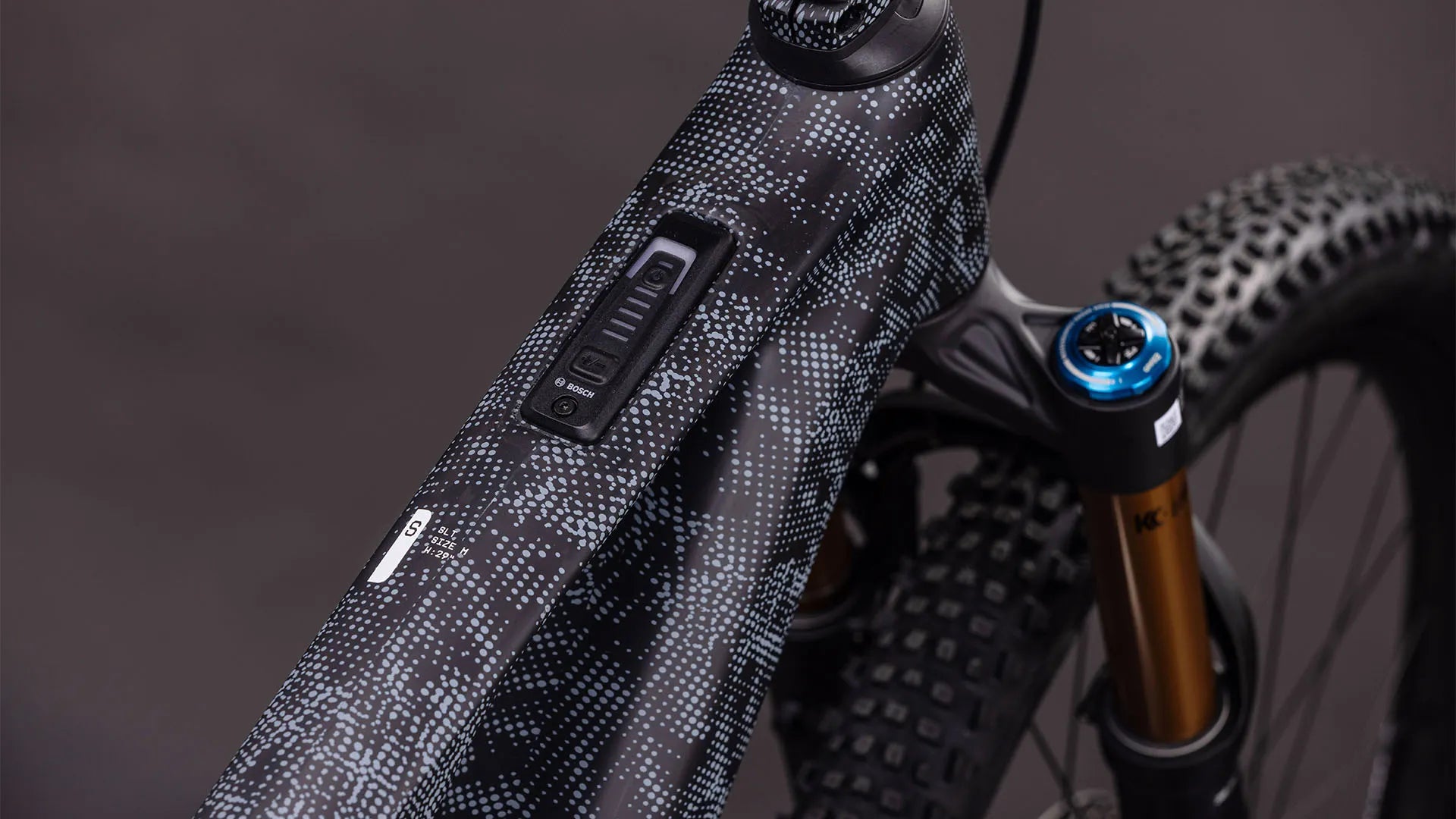 Nahaufnahme eines Bosch AMS HYBRID ONE44 C:68X SLX 400X
E-Bike-Rahmens im modernen Design mit Anzeige und Vorderradfederung, geeignet für Mountainbiking.