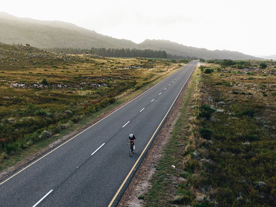 Radfahrer auf einsamer Landstraße in hügeliger Landschaft, Specialized Rennrad für Ausdauerfahrten.