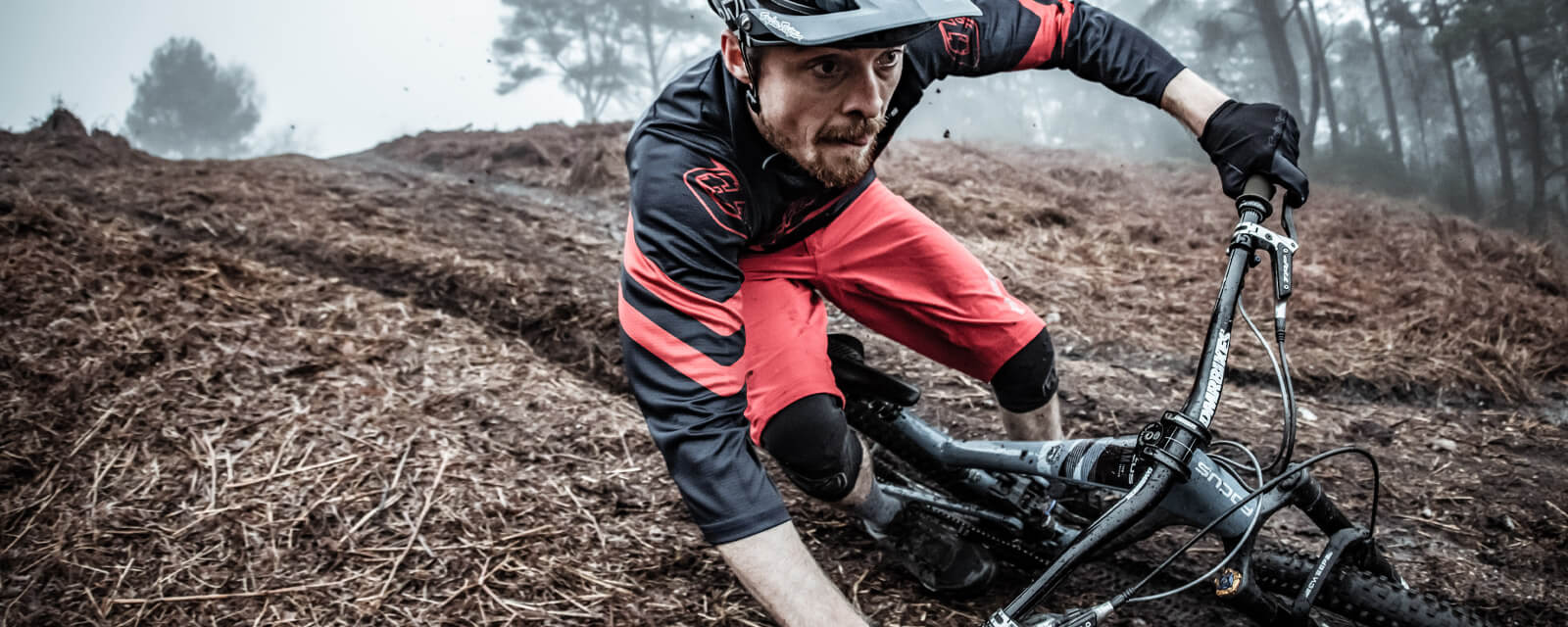 Mountainbiker mit Troy Lee Designs Outfit auf schlammigem Weg in Aktion.