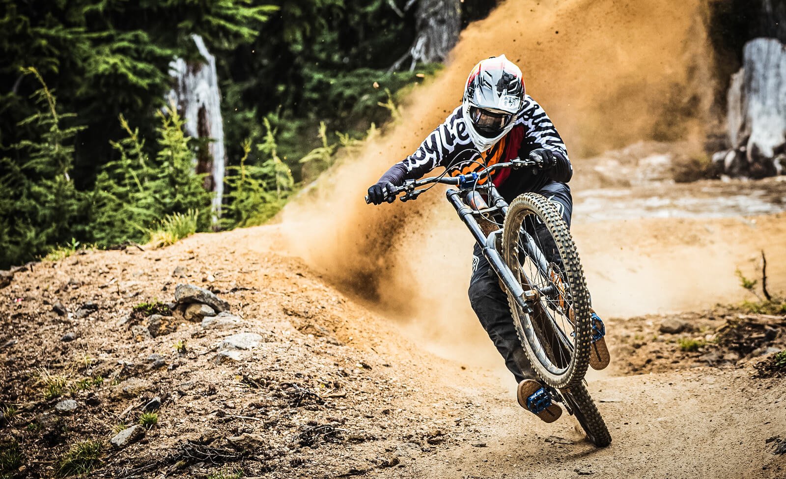 Mountainbiker in Troy Lee Gear meistert kurvige, sandige Strecke. Geeignet für actionreiche Downhill-Abenteuer.