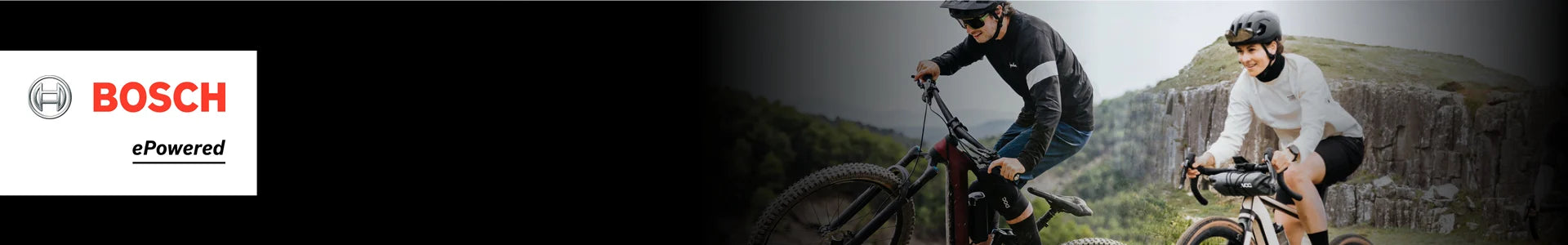 Zwei Personen fahren Berg-E-Bikes mit Bosch-Motoren in einer natürlichen Umgebung. Links das Bosch-Logo.