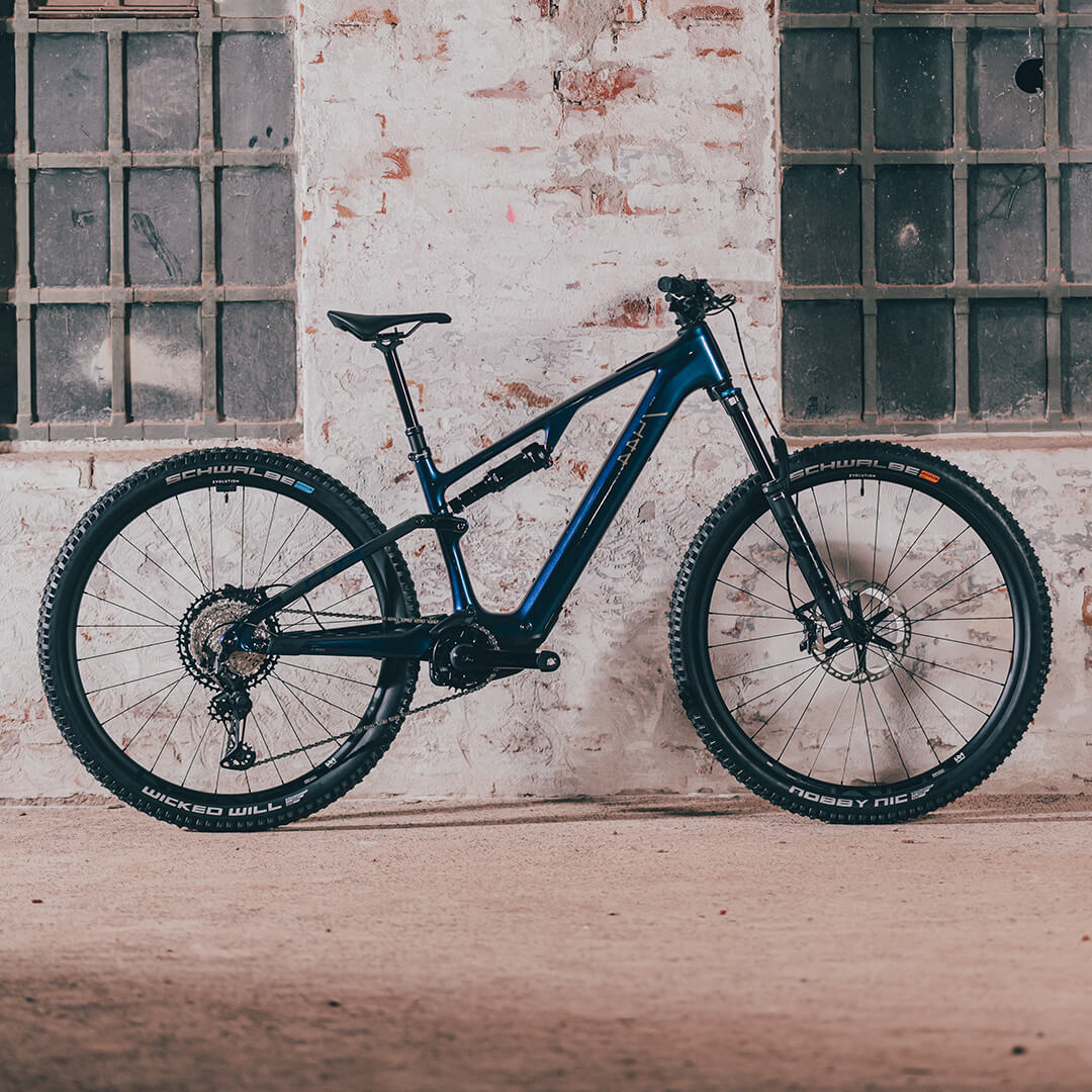 Blaues Cube-Mountainbike 2025 Modell, steht vor einer Backsteinwand. Ideal für Geländefahrten. Reifen: Schwalbe.