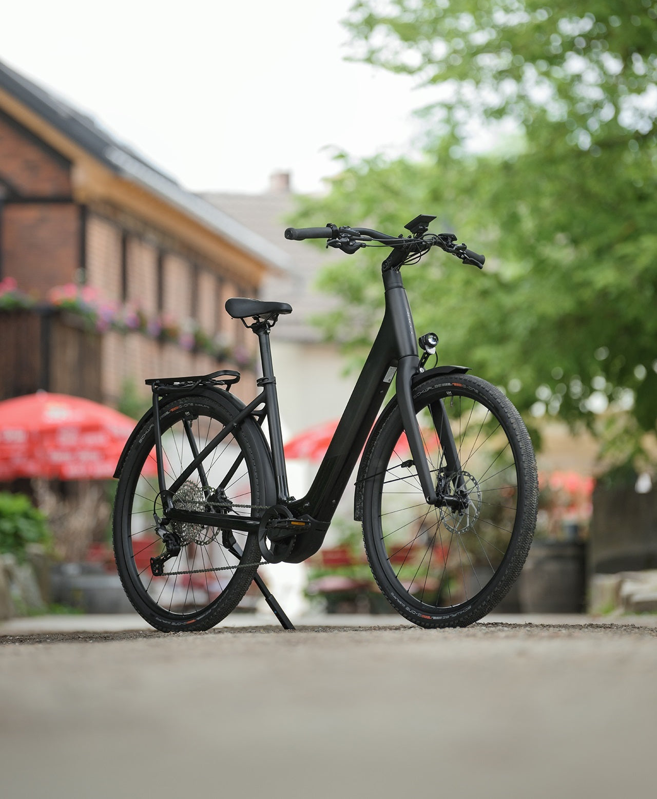 Schwarzes E-Bike mit tiefem Einstieg und Scheibenbremsen, perfekt für Stadtfahrten. Im Hintergrund eine gemütliche Straßenszene.