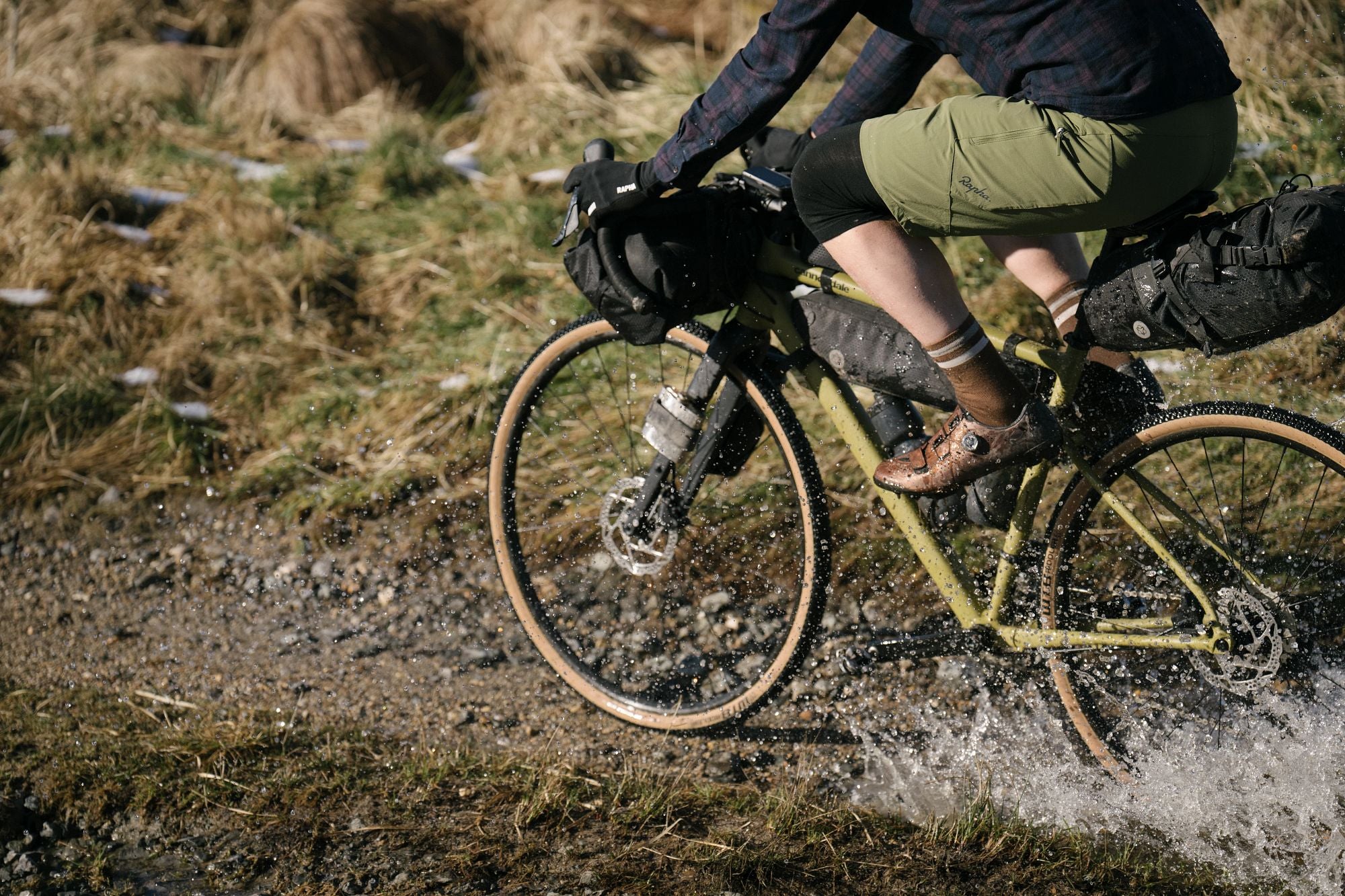 Person auf Cannondale Gravel Bike fährt durch Pfütze, geeignet für Offroad-Abenteuer.