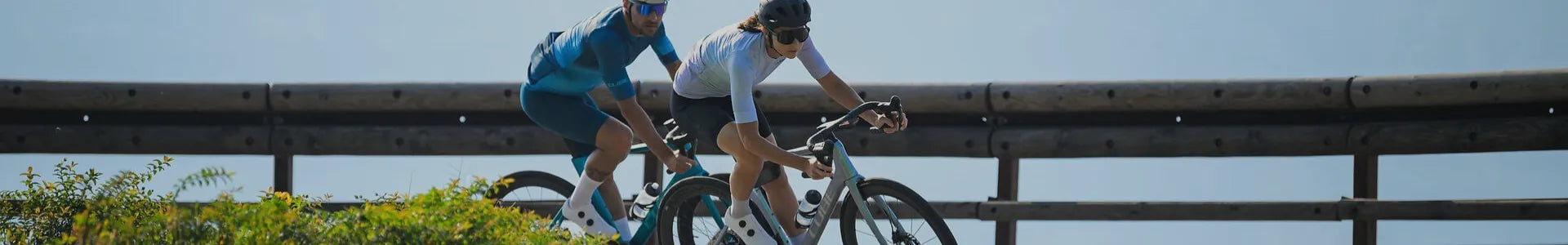 Zwei Personen fahren ein Cube Agree 2026 Rennrad auf einer kurvigen Straße mit Holzgeländer – sportliche Haltung, volle Performance.