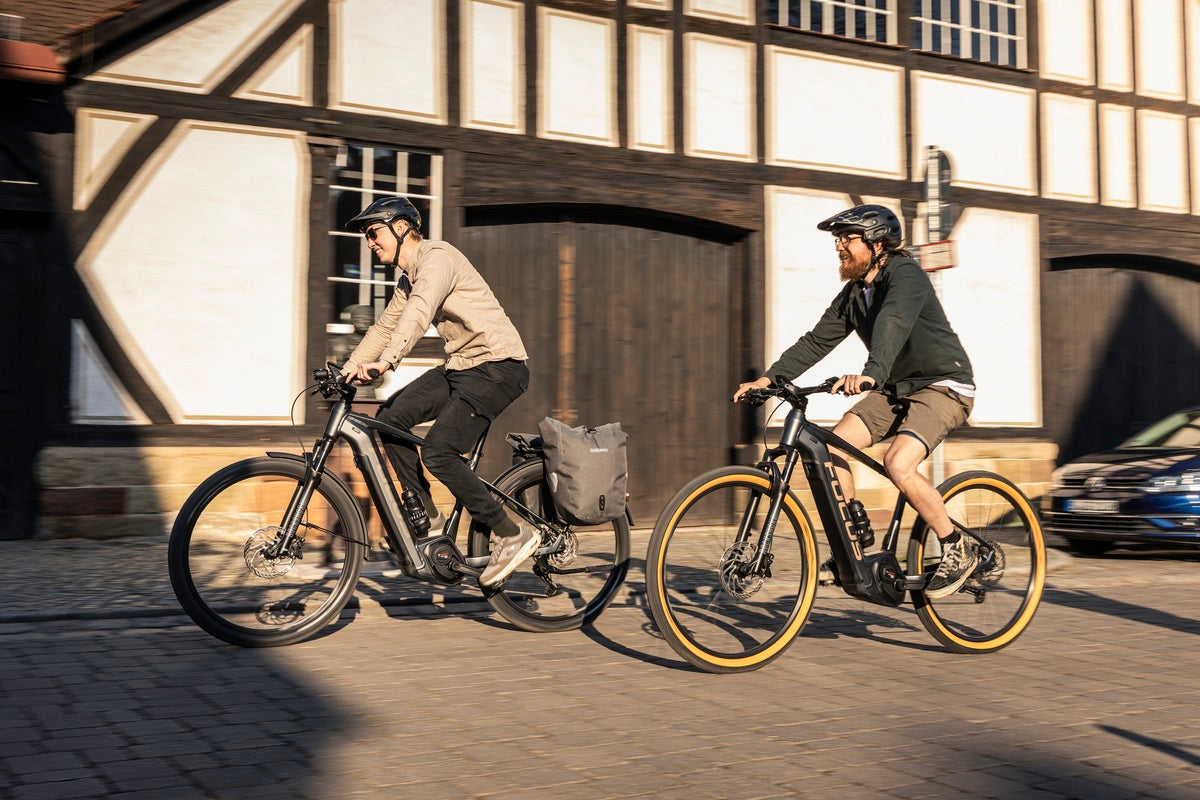 Zwei Personen fahren auf Focus E-MTB Hardtails durch eine städtische Straße bei Fachwerkhäusern.