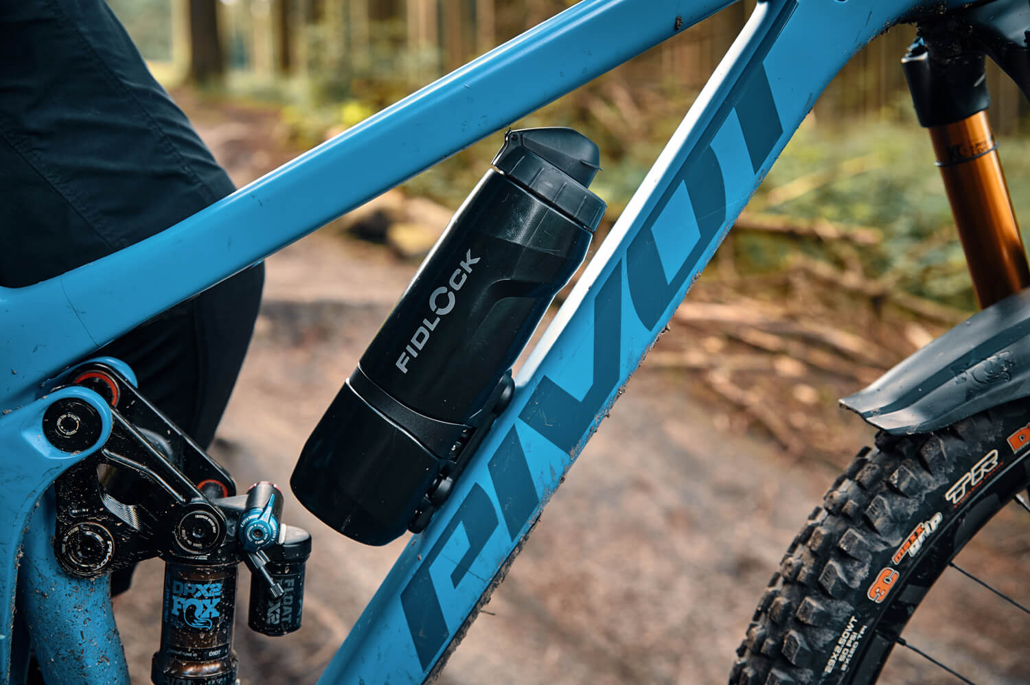 Blaues Mountainbike mit schwarzer Fidlock-Trinkflasche am Rahmen, geeignet für Offroad-Abenteuer.