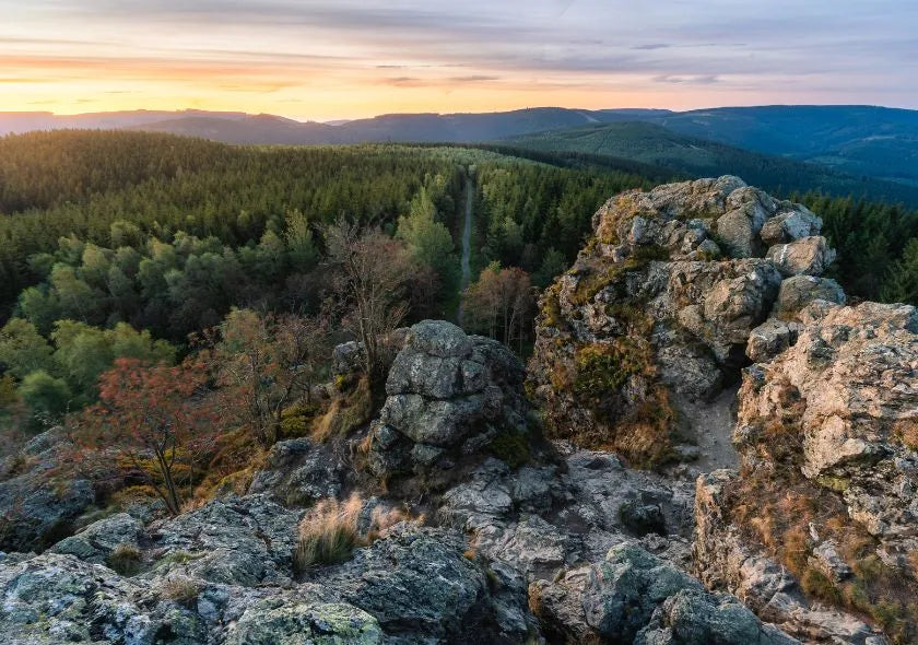 Felsige Aussicht mit Wäldern im Sonnenuntergang; ideal für Wanderer und Naturfreunde.