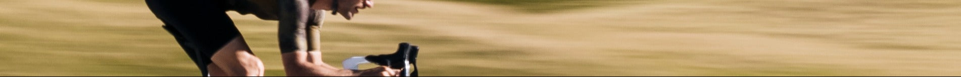 Ein Radfahrer in sportlicher Haltung auf einem Fahrrad, dynamische Unschärfe im Hintergrund, passend für Gravel-Biking.