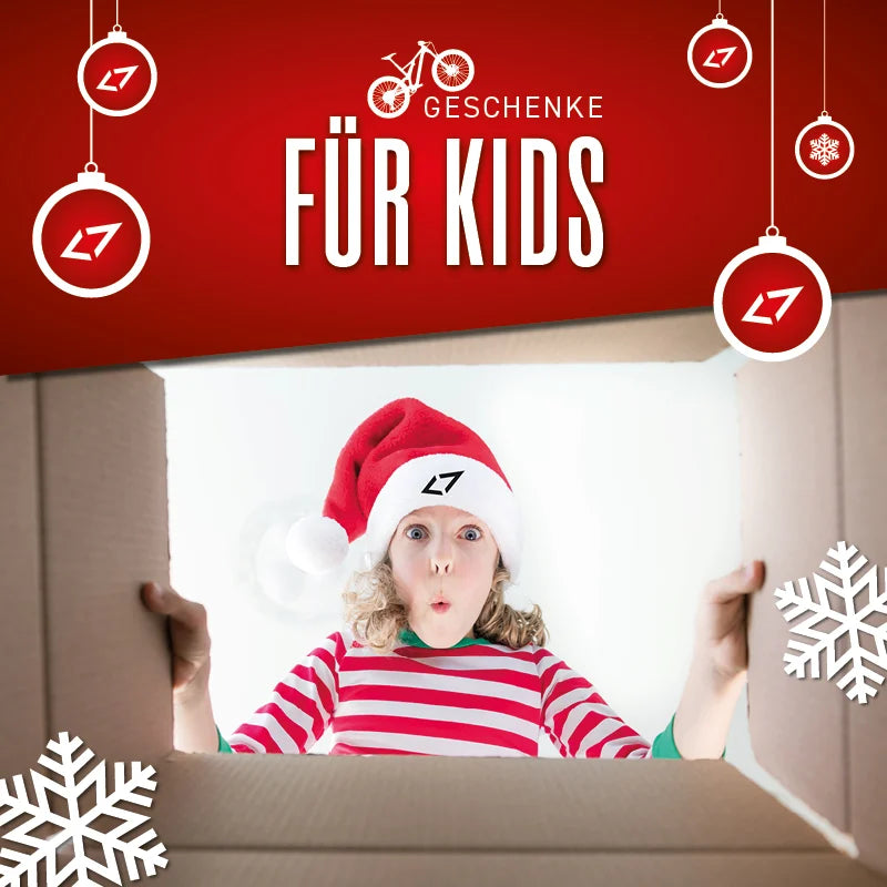 Kind in rotem Streifenpullover und Weihnachtsmütze mit LT-Logo schaut aus Karton, umringt von Weihnachtsdekorationen.