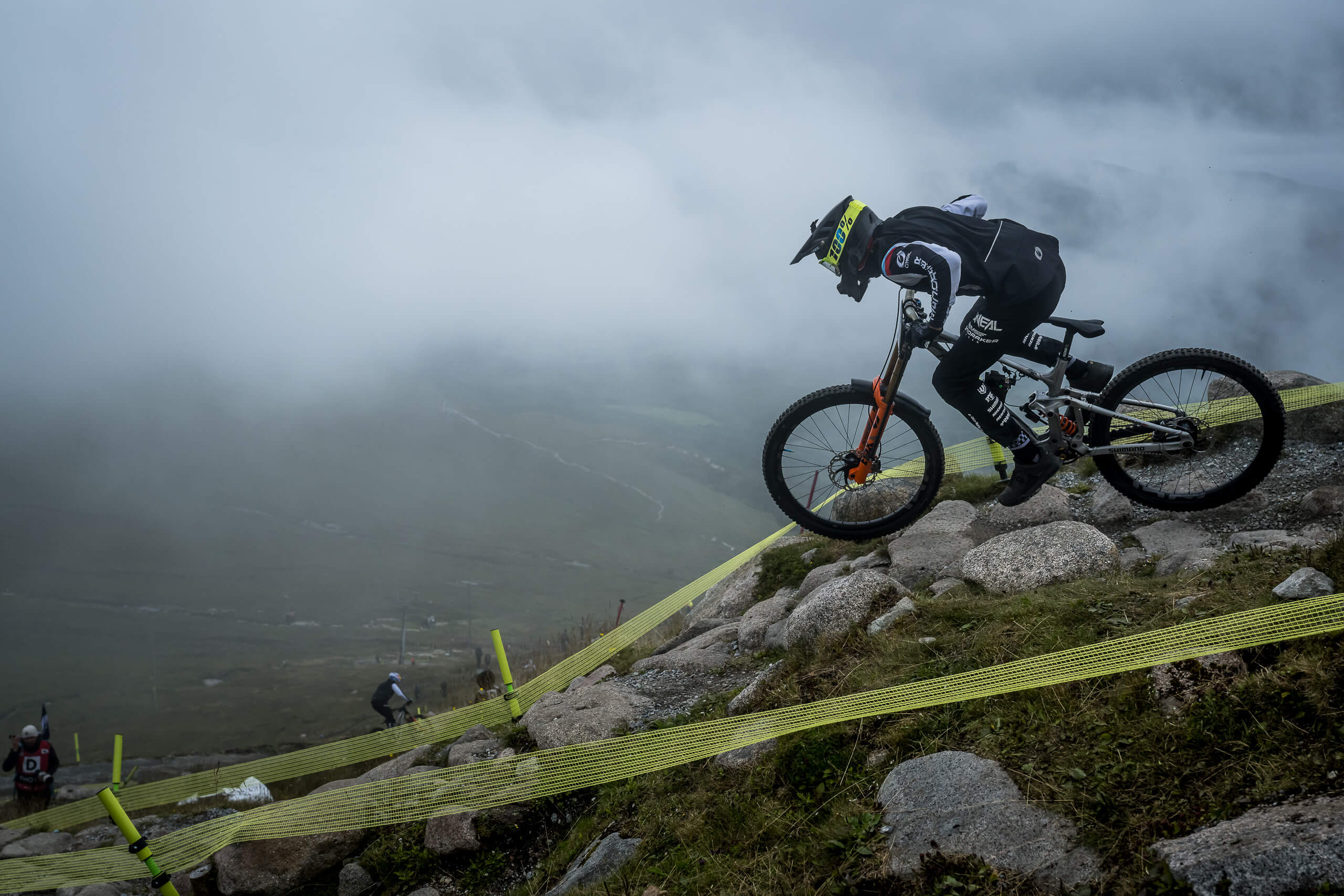 Radfahrer auf Mondraker Summum Mountainbike meistert steinigen Downhill bei Nebel. Ideal für Abenteuersportler.