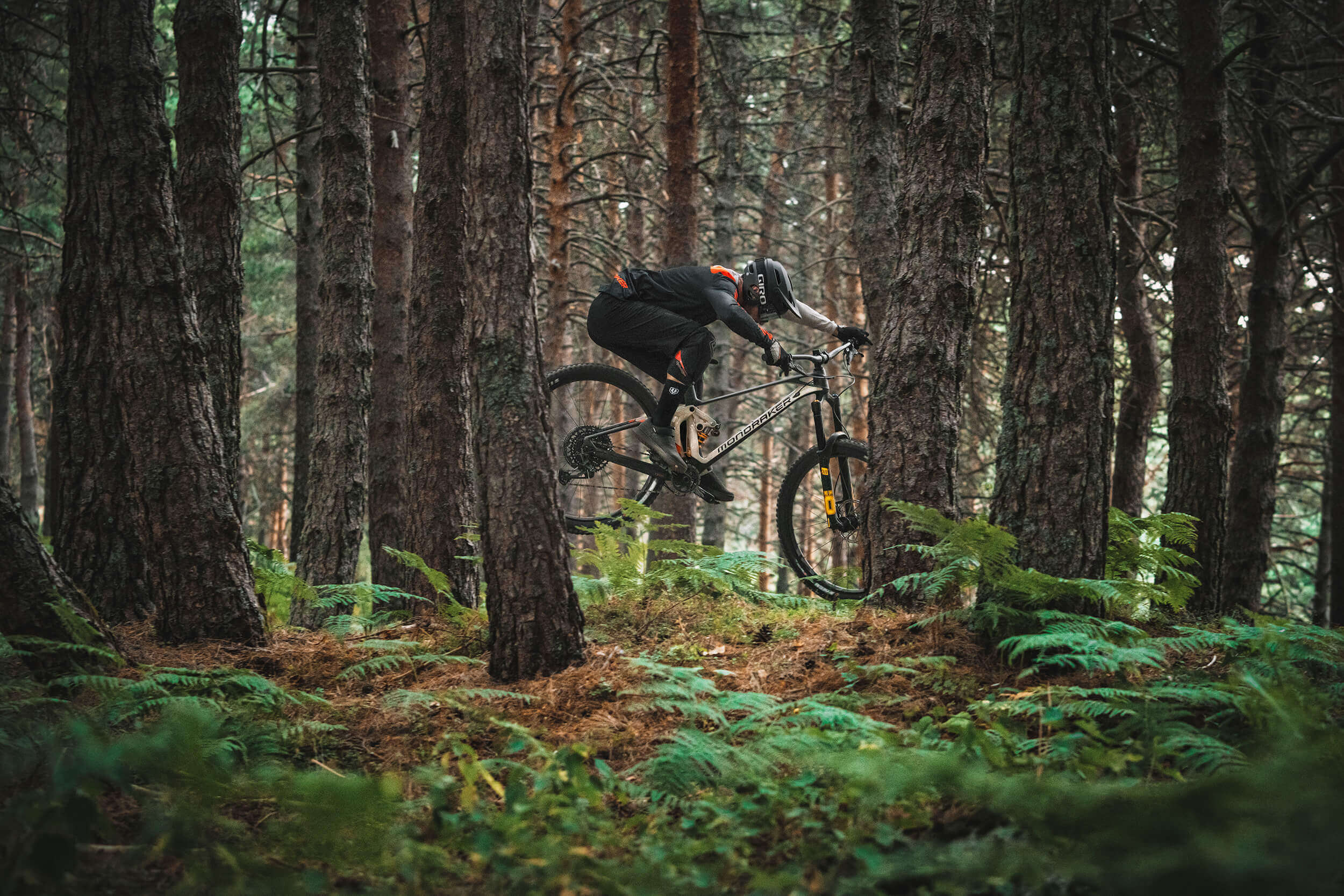 Radfahrer auf Mondraker Superfoxy Mountainbike, fährt im dichten Wald, ideal für Geländefahrten und abenteuerlustige Biker.