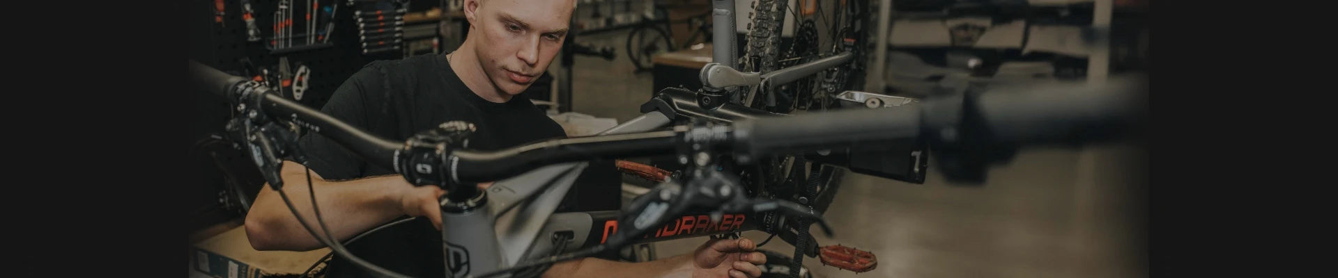 Mechaniker bei der Inspektion eines Mondraker Mountainbikes in einer Werkstattumgebung.