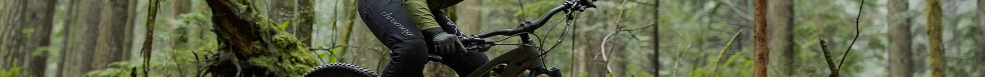 Person auf einem Trek E-Mountainbike fährt durch einen dichten Wald, Fokus auf das Rad und die bewaldete Umgebung.