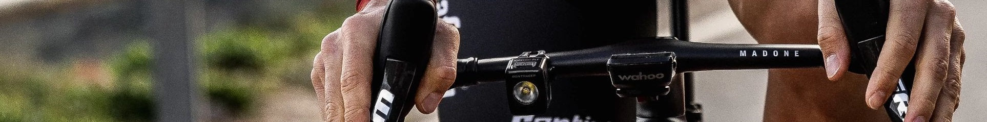 Nahaufnahme eines Madone-Lenkerbereichs mit Bontrager-Licht und Wahoo-Computer, gehalten von Händen im Rennradhaltung.