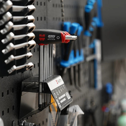 In einer Werkstatt an der Wand befestigte HEYCO Sechskantschlüssel mit ergonomischem Griff, umgeben von Schraubwerkzeugen.