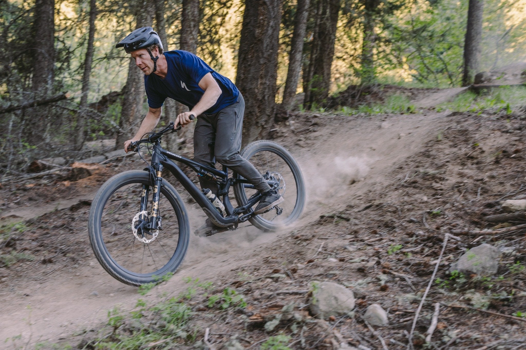 Mann fährt Specialized Stumpjumper Mountainbike auf Waldweg, geeignet für Offroad- und Trail-Enthusiasten.
