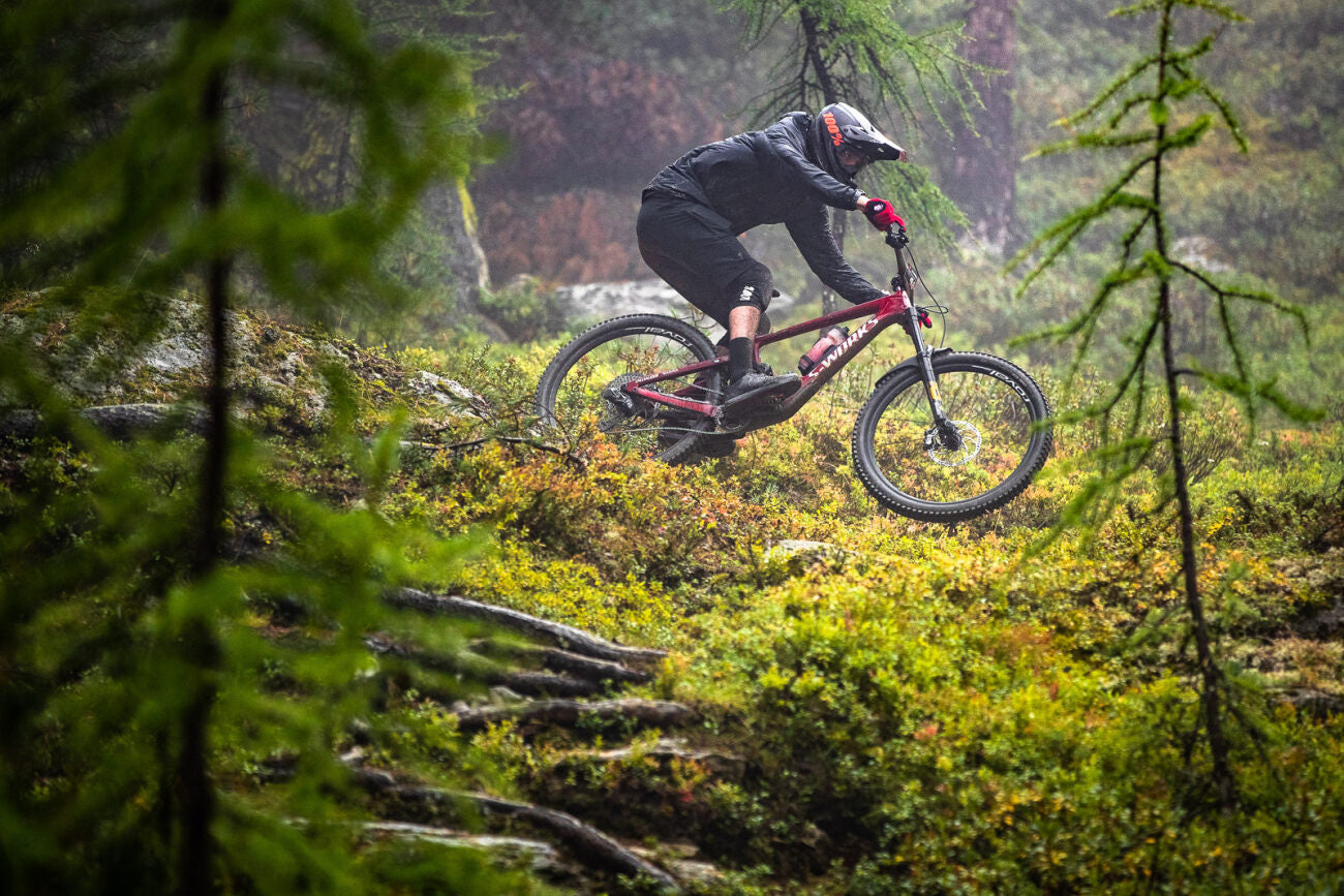 Mountainbiker auf einem Specialized S-Works Fully im Waldgelände bei nassem Wetter.