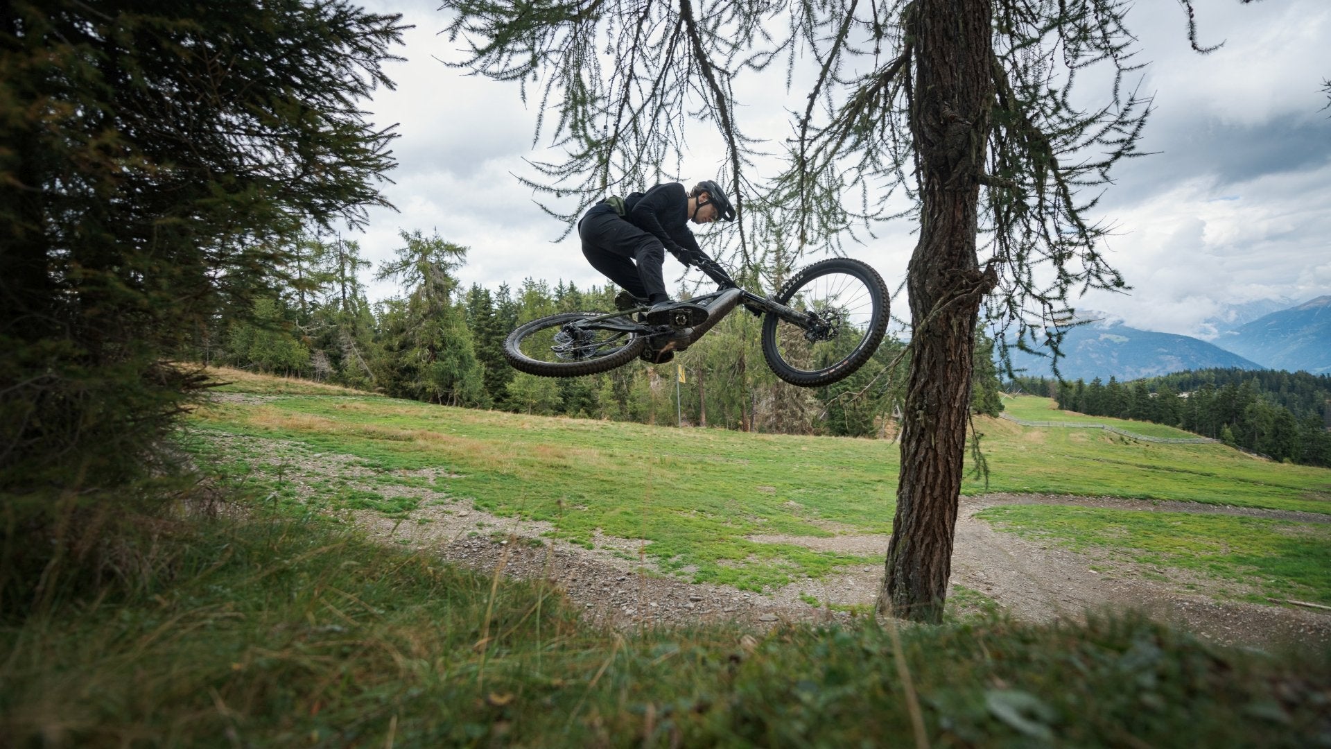 Mountainbiker springt im Wald über Hügel auf einem Trail. Ideal für Outdoor- und Actionfans.