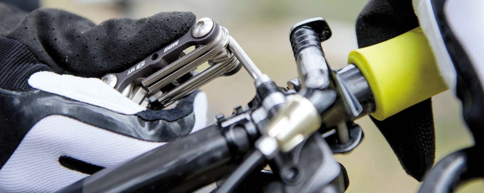 Fahrrad-Multitool Topeak Mini 9 in Aktion, gehalten von behandschuhter Hand. Ideal für Radfahrer zur schnellen Wartung.